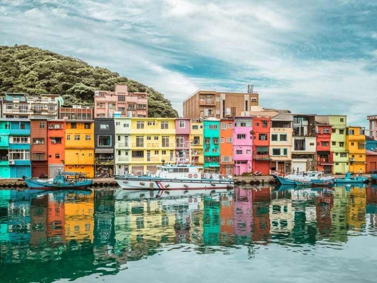ทัศนียภาพท่าเรือประมงเจิ้งปิง ที่เป็นพิกัดยอดฮิตในการเที่ยวไต้หวัน โดดเด่นด้วยอาคารหลากสีสันสไตล์คัลเลอร์ฟูลเรียงรายริมน้ำ
