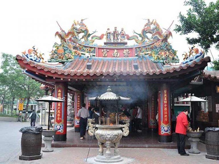 บรรยากาศหน้าวิหารวัดจื่อหนานกง ที่เที่ยวไต้หวัน ที่มีงานประติมากรรมมังกรคู่บนหลังคาและกระถางธูปโลหะขนาดใหญ่ท่ามกลางควันธูปจากผู้มาขอพร