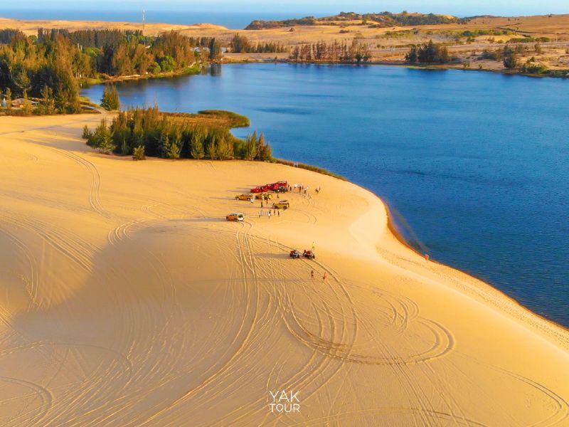 ทัศนียภาพมุมสูงของเนินทรายสีทองกว้างใหญ่ขนานกับผืนน้ำสีฟ้าใสที่เมืองมุยเน่ (Mui Ne) พร้อมกิจกรรมรถเอทีวีและรถจี๊ปบนเนินทราย