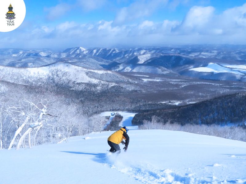 ผู้ชายกำลังเล่นสกีที่ ซาโฮโระ สกีรีสอร์ท ฉากหลังคือวิวอันสวยงาม