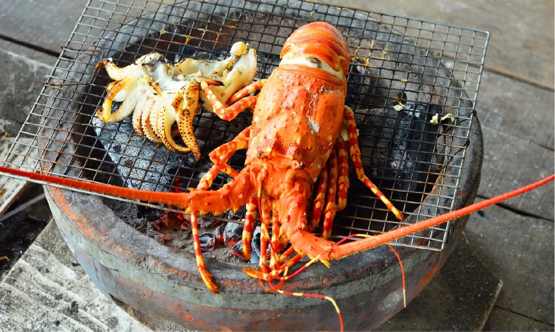 กุ้งมังกรตัวโตย่างสดๆ บนเตาถ่านร้อนๆ หอมฉุยที่ร้านอาหารริมหาดญาจาง