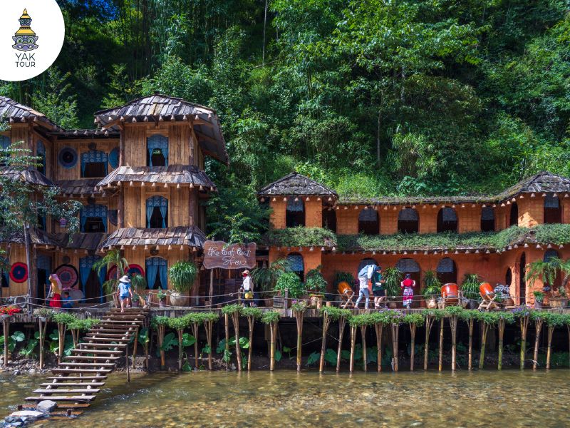 บรรยากาศหมู่บ้านกั๊ตกั๊ต (Cat Cat Village) ในเมืองซาปา แสดงอาคารไม้ดีไซน์พื้นเมืองตั้งตระหง่านริมลำธารใส รายล้อมด้วยความเขียวขจีของต้นไม้ท่ามกลางหุบเขา