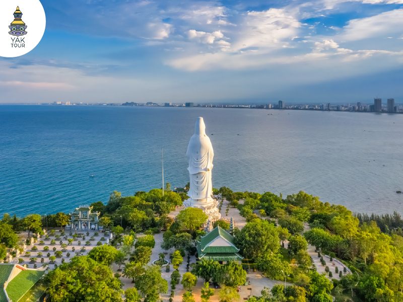 องค์เจ้าแม่กวนอิมสีขาวขนาดใหญ่ตั้งตระหง่านริมชายฝั่งทะเลท่ามกลางบรรยากาศเงียบสงบและวิวพาโนรามาของอ่าวดานัง