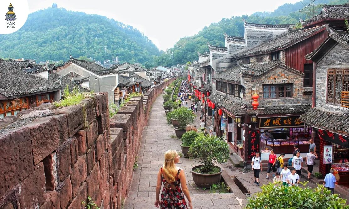 ทางเดินบนกำแพงเมืองเก่าที่มีทัศนียภาพอาคารไม้โบราณและร้านค้า