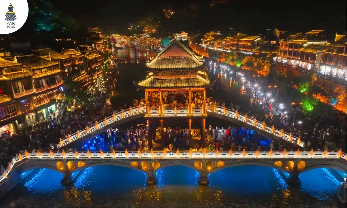 ทัศนียภาพยามค่ำคืนของสะพานโบราณและบ้านเรือนริมน้ำที่ประดับไฟสวยงาม