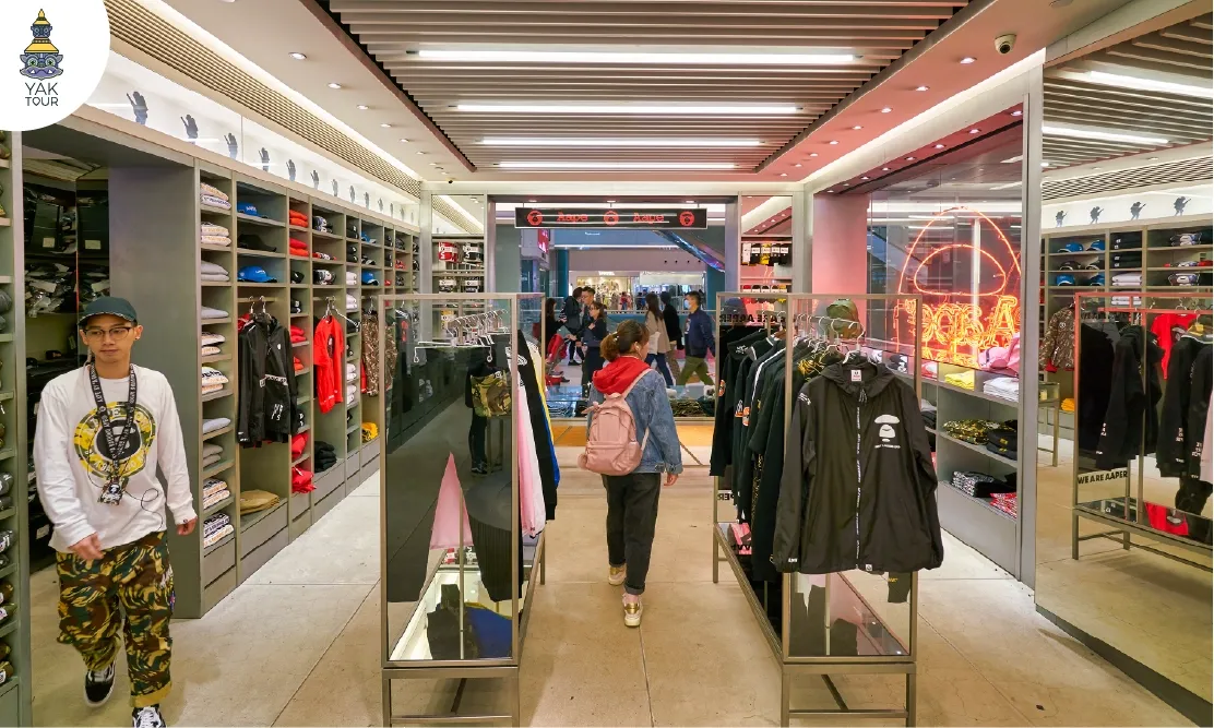 ผู้หญิงยืนเลือกเสื้อผ้าดีไซน์ทันสมัยในร้าน Multi-brand ย่านมงก๊ก