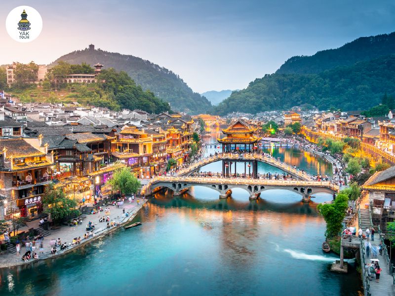 ทัศนียภาพยามค่ำคืนของเมืองโบราณเฟิ่งหวง (Fenghuang Ancient Town) ริมแม่น้ำโถวเจียงพร้อมแสงไฟประดับสะท้อนน้ำ