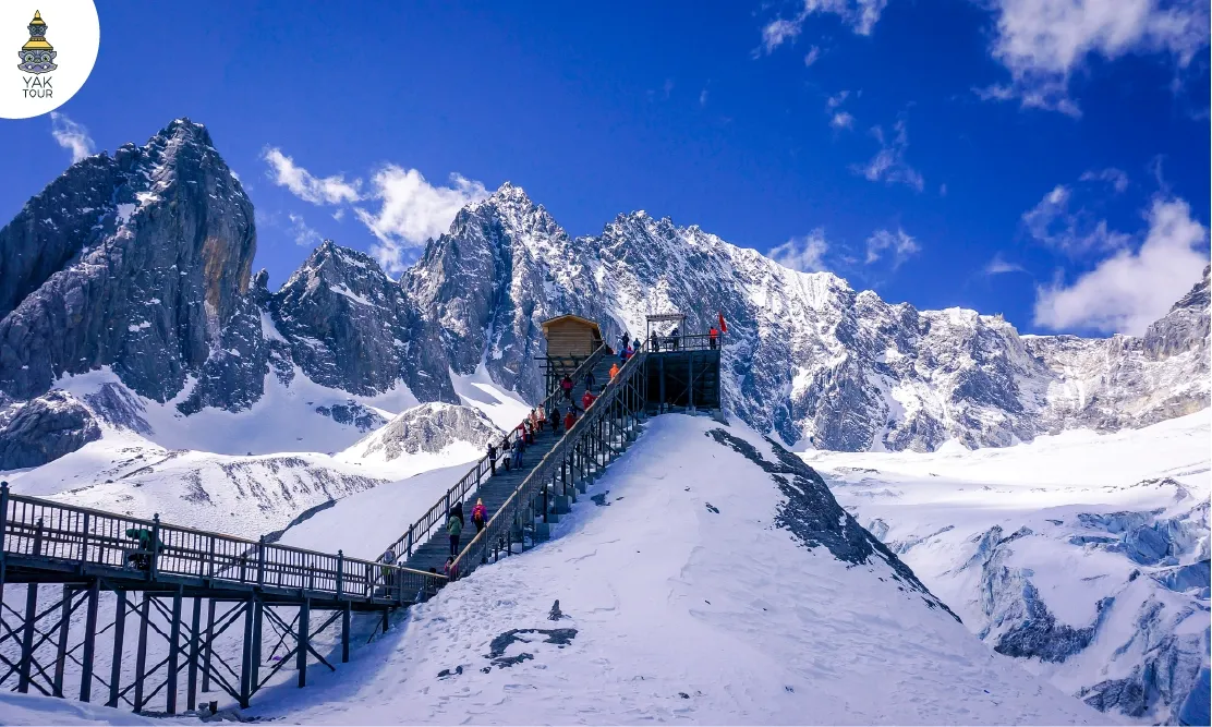 ทางเดินไม้กระดานบนจุดชมวิว Glacier Park ภูเขาหิมะมังกรหยก ลี่เจียง ท่ามกลางหิมะขาวโพลนและท้องฟ้าสีครามที่ความสูง 4,506 เมตร