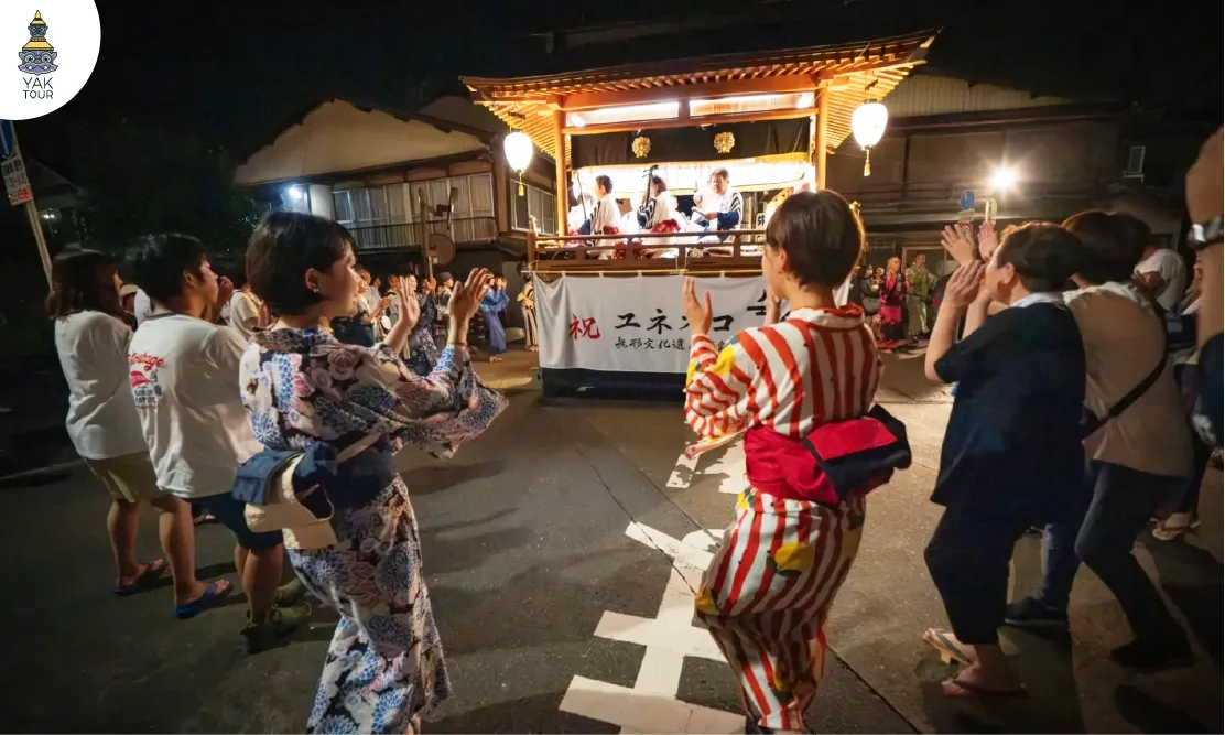 บรรยากาศการเต้นรำในเทศกาล Gujo Odori ยามค่ำคืนหน้าเวทีการแสดงแสงสีทอง 