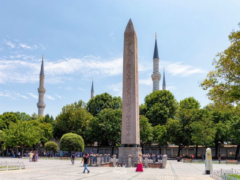 เสาโอเบลิสก์หินแกรนิตทรงสี่เหลี่ยมยอดแหลมสลักลวดลายโบราณ ตั้งตระหง่านอยู่กลางลานจัตุรัสฮิปโปโดรม