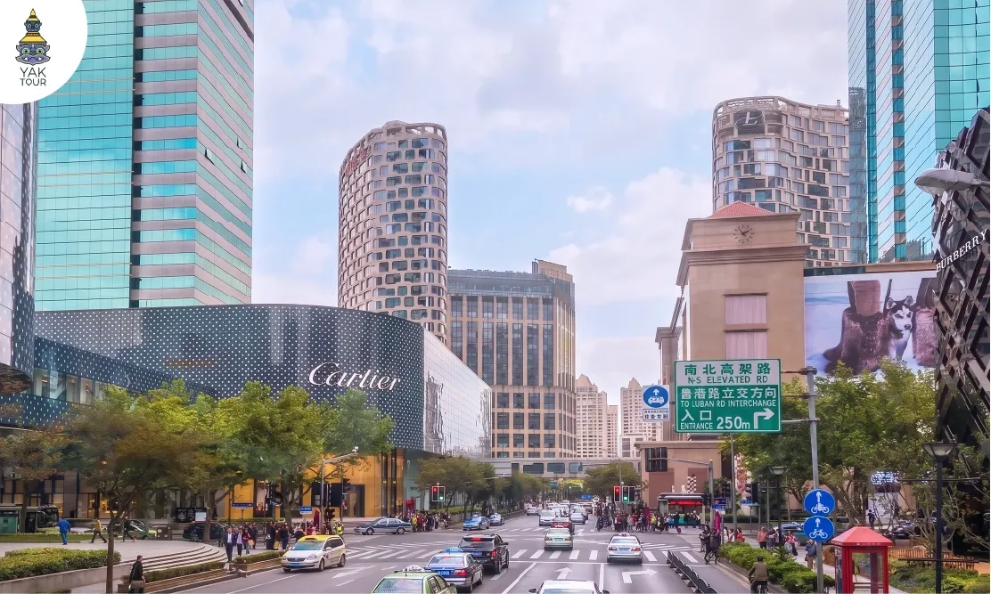 ทัศนียภาพตึกสูงและถนนหวยไห่ลู่ (Huaihai Middle Road) ย่านช้อปปิ้งหรูในเซี่ยงไฮ้ มองเห็นร้าน Flagship Store ของแบรนด์ Cartier และ Burberry ท่ามกลางการจราจรและตึกระฟ้าดีไซน์ทันสมัย
