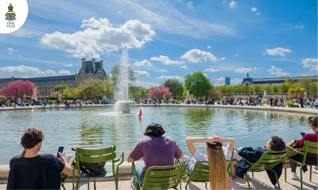 ผู้คนนั่งพักผ่อนบนเก้าอี้สีเขียวรอบน้ำพุในสวน Jardin des Tuileries