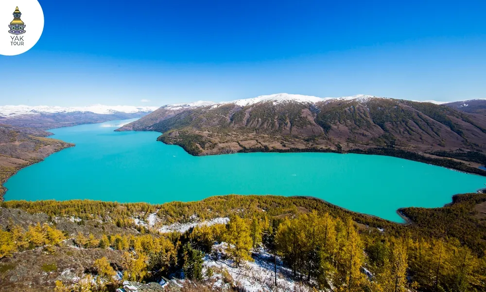 ทิวทัศน์ทะเลสาบสีฟ้าคริสตัลล้อมรอบด้วยป่าสนและยอดเขาหิมะในเขตอุทยานคานาสือแหล่งท่องเที่ยวระดับ 5A ในจีน