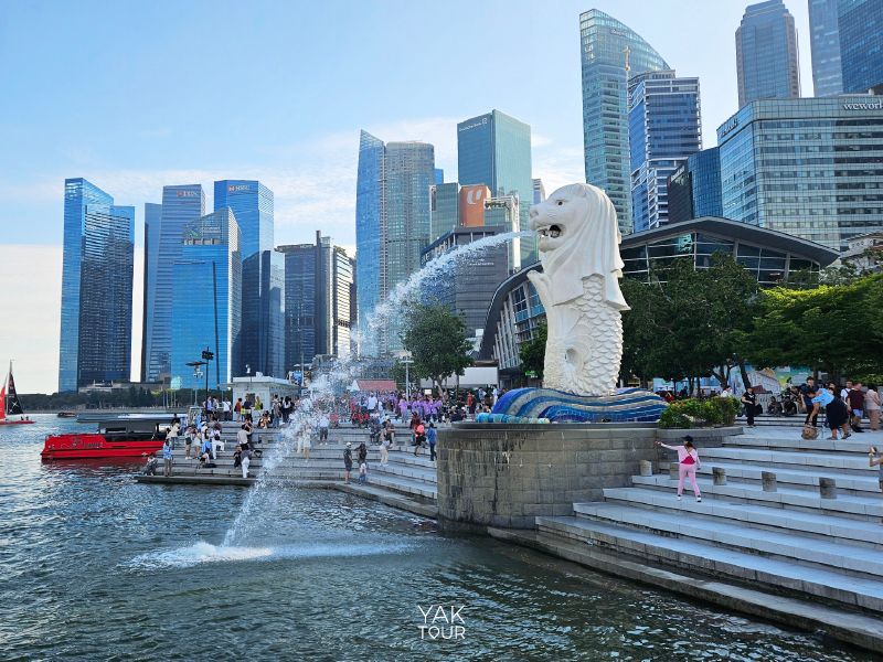 รูปปั้นเมอร์ไลออนพ่นน้ำริมอ่าวมารีน่า ณ เมอร์ไลออน พาร์ค (Merlion Park) โดยมีฉากหลังเป็นตึกระฟ้าของสิงคโปร์
