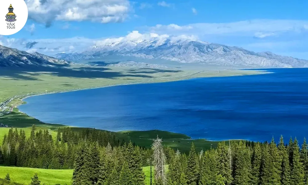 ทัศนียภาพความสวยงามของทะเลสาบไซ่หลี่มู่ (Sailimu Lake) ทะเลสาบสีน้ำเงินเข้มตัดกับทุ่งหญ้าสีเขียวขจี