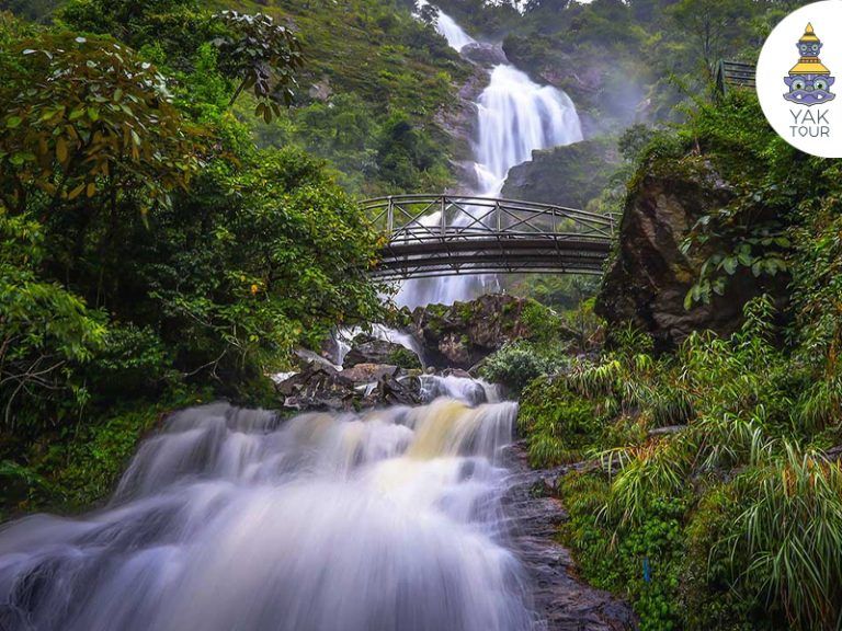 วิวน้ำตกสีเงิน (silver water) ขนาดใหญ่ที่ไหลลงจากหน้าผาสูงท่ามกลางป่าไม้เขียวขจี มีสะพานทางเดินทอดข้ามสายน้ำตกสีขาวโพลน