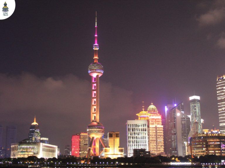 หอไข่มุกตะวันออก (The Oriental Pearl Tower) แลนด์มาร์คริมแม่น้ำหวงผู่ยามค่ำคืน โดดเด่นด้วยลูกบอลทรงไข่มุกส่องสว่างท่ามกลางตึกระฟ้าย่านผู่ตง