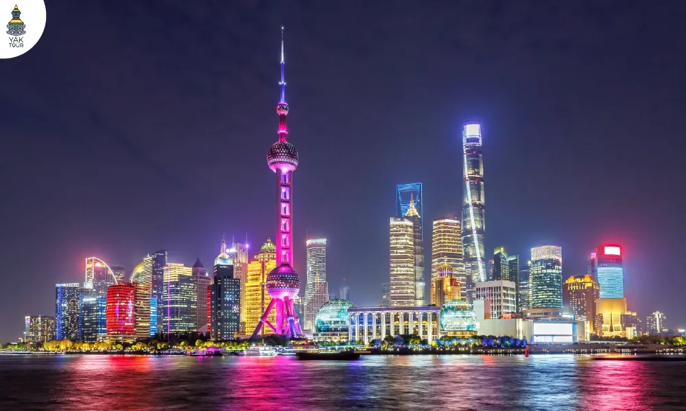 หอไข่มุกตะวันออก (The Oriental Pearl Tower) แลนด์มาร์คริมแม่น้ำหวงผู่ยามค่ำคืน โดดเด่นด้วยลูกบอลทรงไข่มุกส่องสว่างท่ามกลางตึกระฟ้าย่านผู่ตง