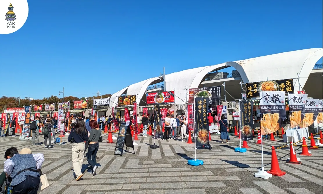นักท่องเที่ยวยืนเลือกซื้อราเมนจากบูธต่างๆ ที่มาร่วมออกร้านในเทศกาล Tokyo Ramen Festa ณ สวนสาธารณะ Komazawa Olympic Park กรุงโตเกียว สำหรับทริป เที่ยวญี่ปุ่น ตุลาคม 2026