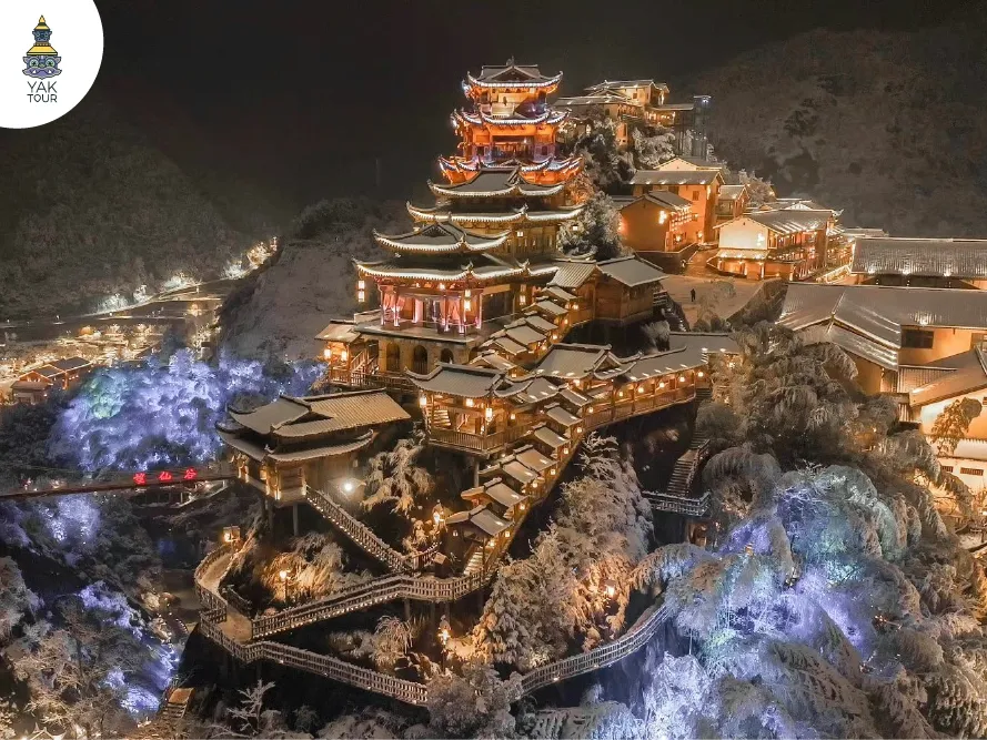 แสงไฟยามค่ำคืนจากอาคารโบราณบนหน้าผาหุบเขาเทวดาที่ปกคลุมด้วยหิมะ