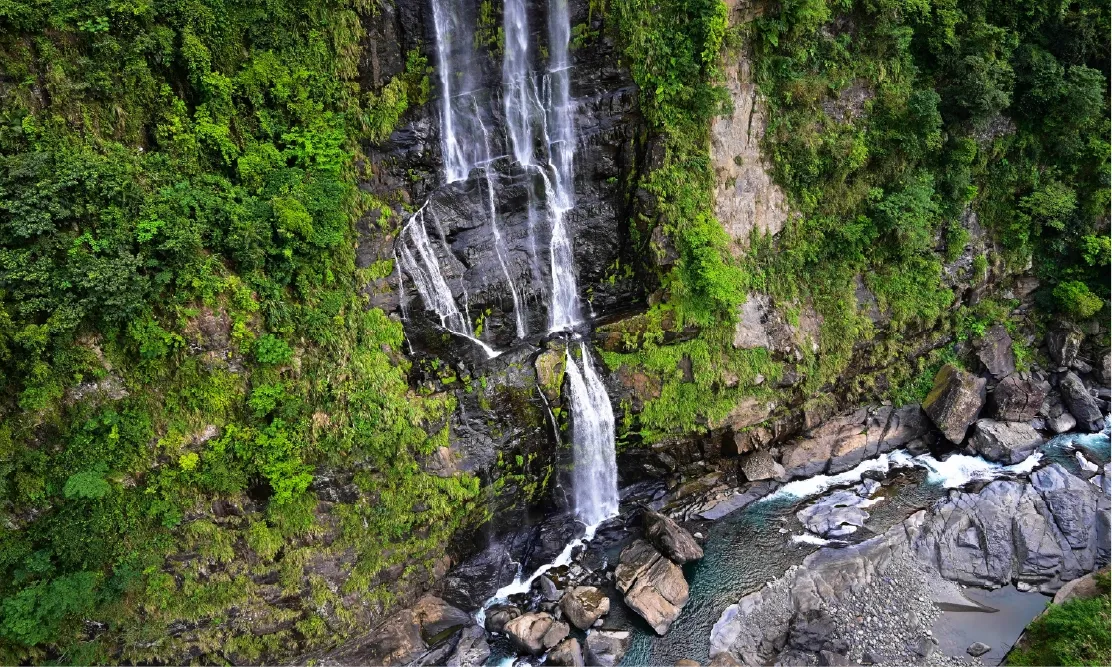 ภาพถ่ายโดรนมุมสูง (Drone View) เผยให้เห็นน้ำตกอูไหล (Wulai Waterfall) สายน้ำสีขาวตกลงมาจากหน้าผาสูงชันที่ปกคลุมด้วยผืนป่าดิบชื้นสีเขียวขจีอย่างยิ่งใหญ่