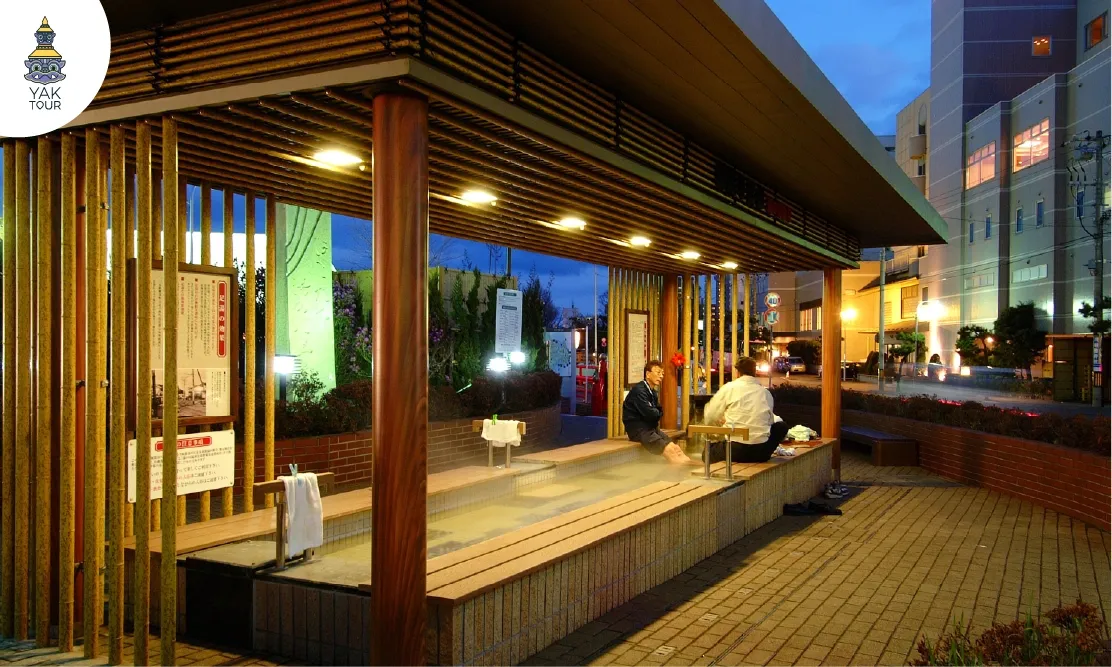 นักท่องเที่ยวนั่งแช่เท้าผ่อนคลายที่บ่อน้ำพุร้อนสาธารณะในย่านยูโนะคาวะออนเซ็น